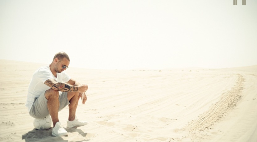 Foto Wesley Sneijder zit op bal in het zand
